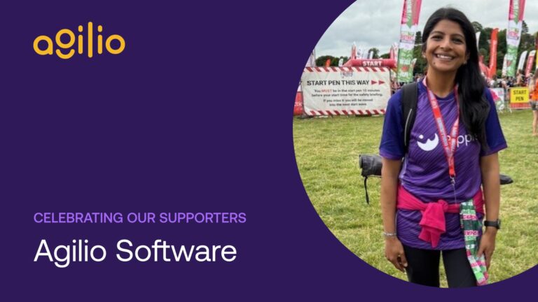 A smiling fundraiser in a purple Ripple t-shirt stands at a race start area, celebrating their support for Ripple Suicide Prevention