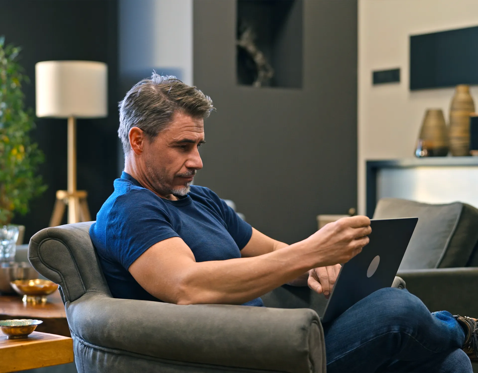 Middle-aged man browsing on a laptop in a home environment.