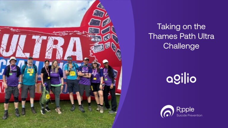 Eight people in Ripple t-shirts wearing medals, standing on grass in front of a large red inflatable Ultra Challenge arch